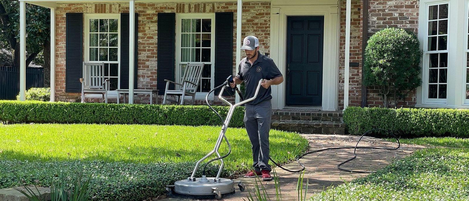 A Goodsmith technician cleaning the brick walkway in front of a Houston home