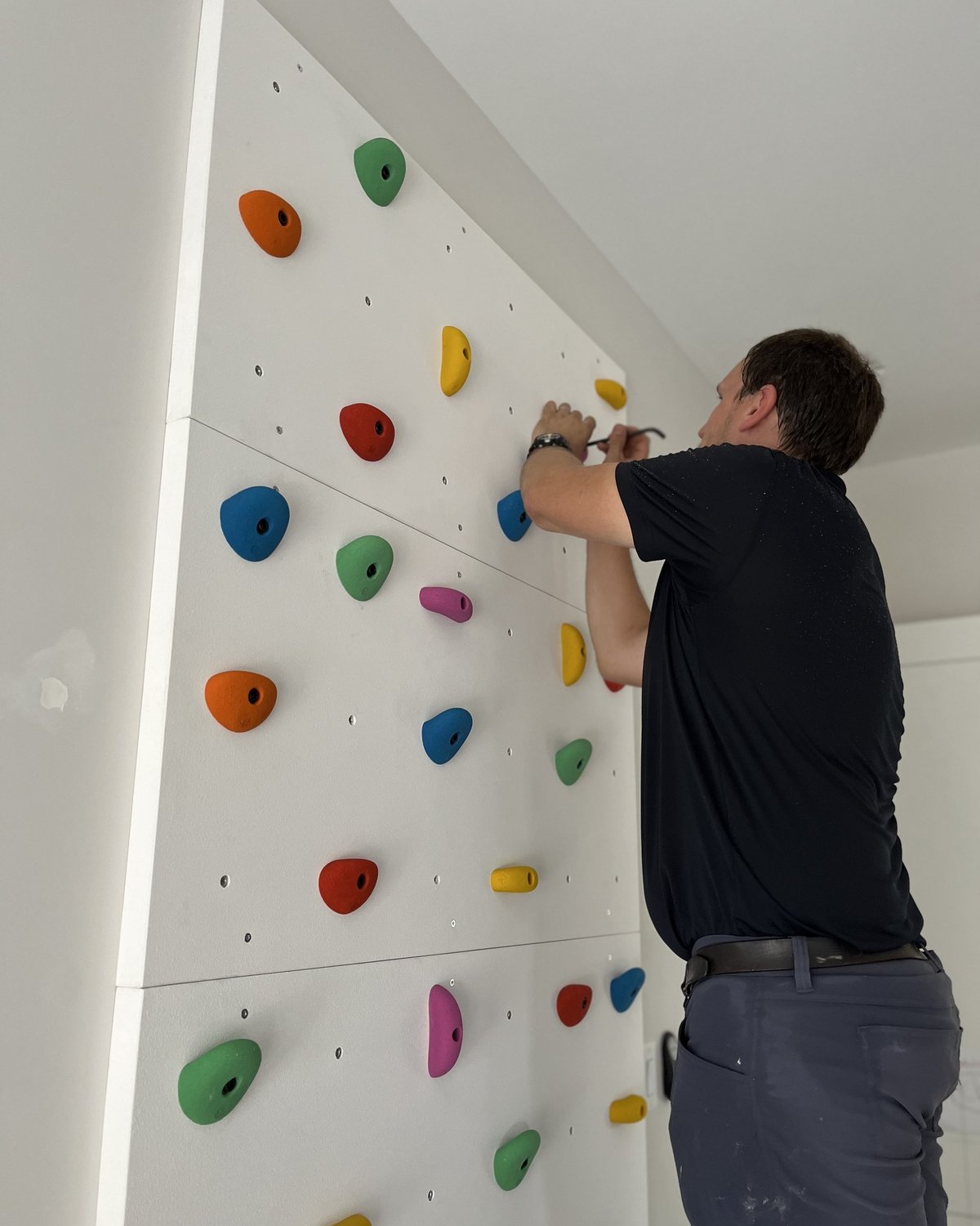 A Goodsmith technician installing a climbing wall in a family's home